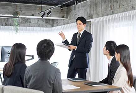 5人の社員が資料を見ながら会議をしている様子の写真