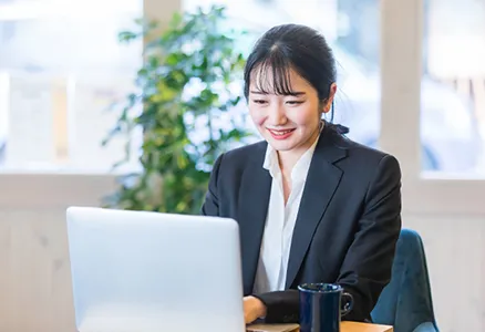 ノートパソコンに向かって作業をしている女性社員の写真