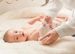 白い毛布の上に赤ちゃんが寝転んでいる写真