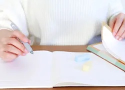 ノートを開いて電卓をたたいている人物の手元の写真