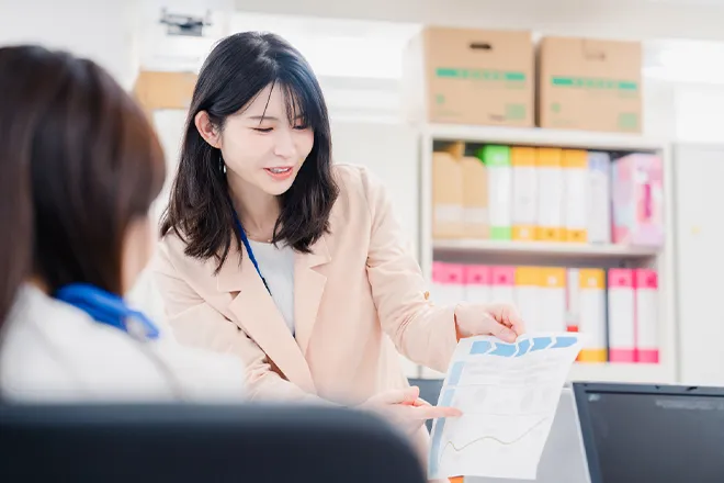 資料を指示して説明する女性社員の写真