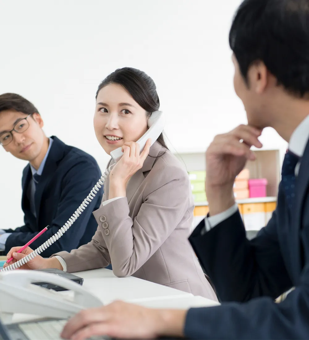 電話対応中の社員とその様子をうかがう2人の社員の写真